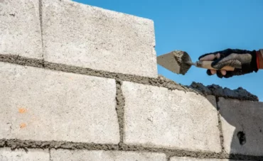 Maçon en train de monter un mur en parpaing